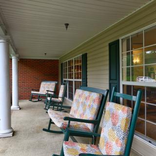 A cozy porch with colorful rocking chairs and white columns.