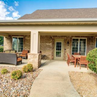 A welcoming house with a covered porch and comfortable patio furniture, surrounded by neat landscaping.