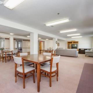 Spacious dining and sitting area with tables, chairs, and sofas under bright lighting.