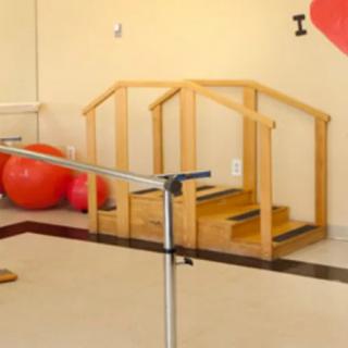 A therapy room equipped with balance bars, wooden stairs, and exercise balls for physical rehabilitation.