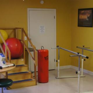 A physical therapy room featuring parallel bars and rehabilitation equipment.