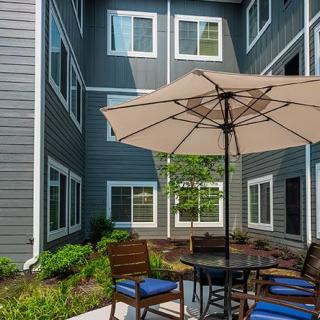 A cozy patio area with an umbrella, chairs, and a table set against a residential building.