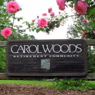 Entrance sign for Carol Woods Retirement Community surrounded by pink roses.