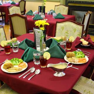 A formal dining table set with plates of food and neatly folded napkins.