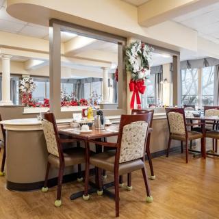 A cozy dining room decorated with festive holiday ornaments, featuring tables and chairs arranged neatly.