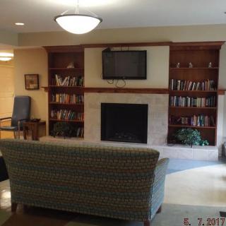 A cozy living room featuring a fireplace, television, and bookshelves, with a comfortable sofa for relaxation.