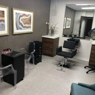 A modern hair salon interior with styling chairs and artwork on the walls.