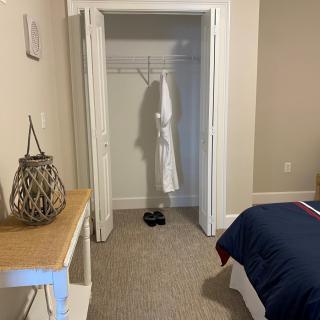 A minimalist bedroom featuring an open closet with a robe hanging inside.