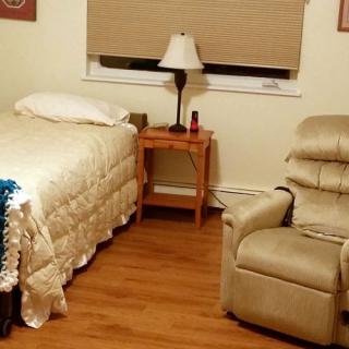 A cozy bedroom with a bed, recliner, and nightstand.