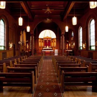 Interior view of a church with wooden pews and a prominent altar.