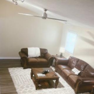 Cozy living room with leather furniture and a ceiling fan.