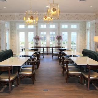 A modern dining area with elegant chandeliers, large windows, and neatly arranged tables and chairs.