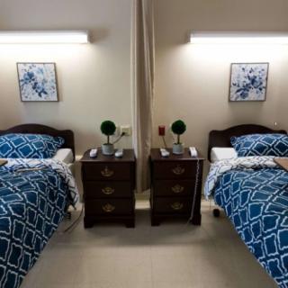 A neatly arranged bedroom with two single beds featuring blue geometric bedding and matching nightstands in between.