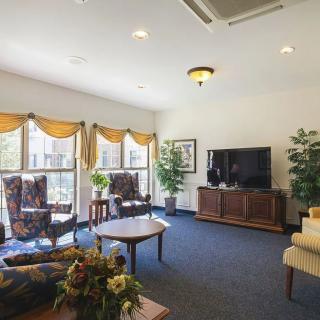 A cozy living room with comfortable seating, a large TV, and bright natural light streaming through the windows.