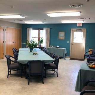 A neatly arranged meeting room with tables and chairs, adorned with plants.