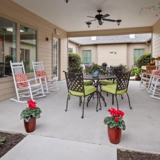 A cozy patio with rocking chairs, a table set, and potted plants.