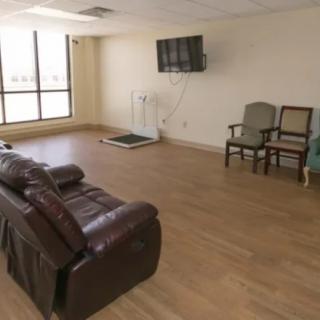A spacious living area with a leather couch, chairs, and a wall-mounted television.