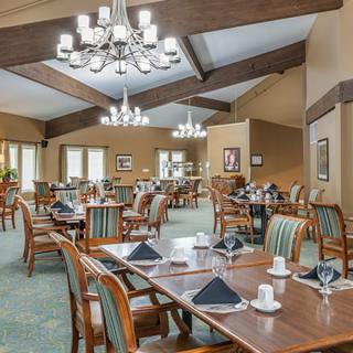 An elegant restaurant dining area with neatly arranged tables and chairs, accented by chandeliers.