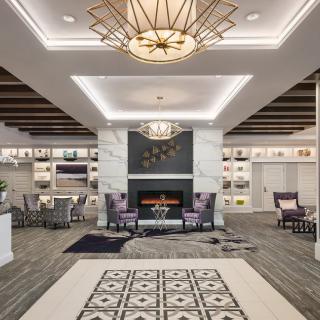 A modern lobby with a stylish fireplace, comfortable seating areas, and a striking chandelier.