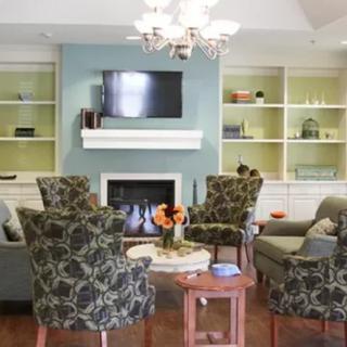 A cozy living room with a seating area arranged around a fireplace and television, complemented by built-in bookshelves.