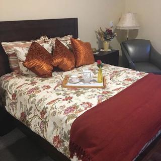A cozy bedroom setup with floral bedding and a decorative tray on the bed.