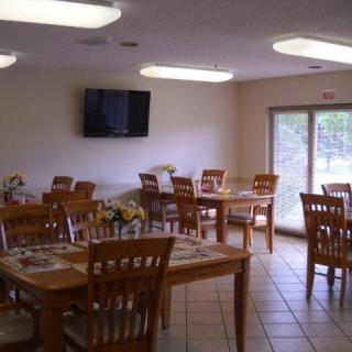 A dining area with wooden tables and chairs, featuring a wall-mounted television.