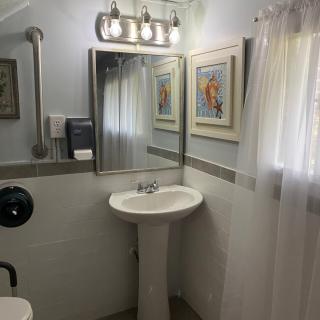 A clean, well-lit bathroom with a pedestal sink and framed artwork on the walls.