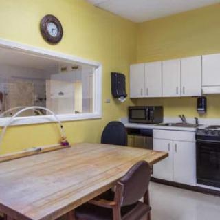 A cozy kitchen featuring yellow walls, a wooden dining table, and modern appliances.