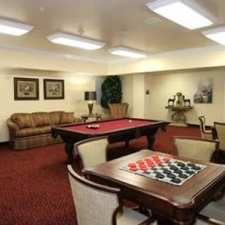A cozy game room with a billiards table and checkers set, featuring comfortable seating and warm lighting.