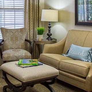 A cozy living room with a comfortable sofa, patterned armchair, and a stylish lamp.