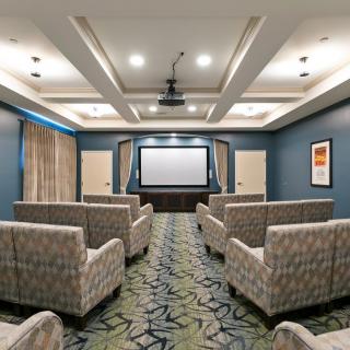 A modern home theater room with comfortable seating and a large projector screen.