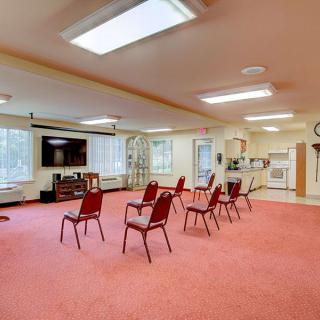 A community meeting space with chairs arranged in a circle, featuring a television and bright indoor lighting.