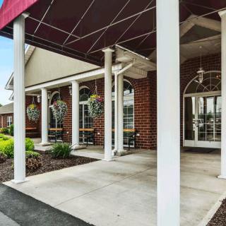 The entrance of a brick building with white columns and a red awning.