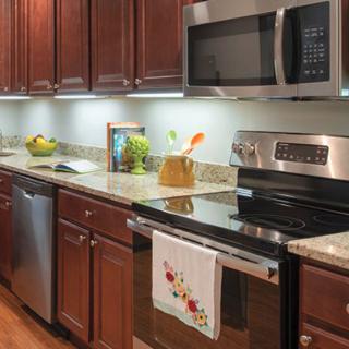 A modern kitchen with stainless steel appliances, dark wood cabinets, and granite countertops.