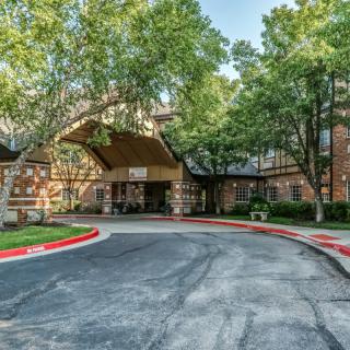 A welcoming building entrance surrounded by trees and a circular driveway.