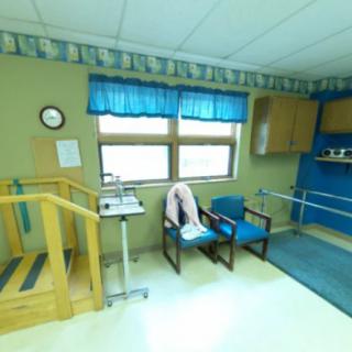 A rehabilitation room equipped with stairs, parallel bars, and chairs designed for physical therapy exercises.