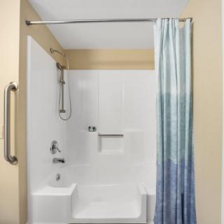 A modern bathroom featuring a bathtub with an overhead shower and a blue gradient curtain.