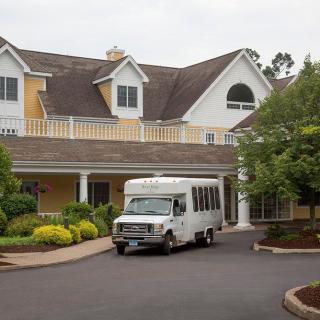 A van is parked in front of a large house with a landscaped driveway.