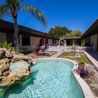 A serene outdoor area featuring a sparkling swimming pool, lush landscaping, and inviting paths amidst beautiful architecture.