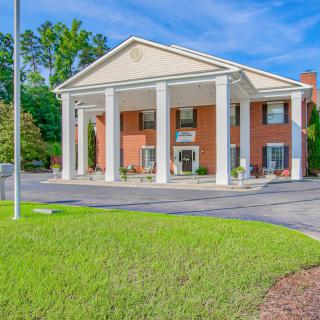 A brick building with large white columns under a clear blue sky.