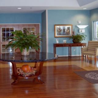 A well-decorated lobby featuring a central table with a potted plant, surrounded by elegant furnishings and hardwood flooring.