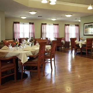 A neatly arranged dining room with several tables and chairs, set for guests.