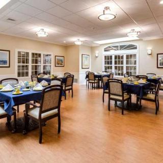 A well-lit dining area with elegantly set tables and chairs, ready for guests.