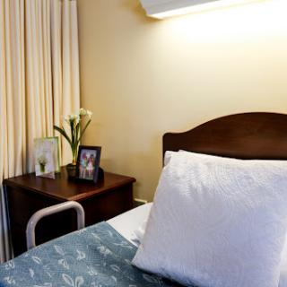 A cozy hospital room featuring a comfortable bed, decorative flowers, and personal touches.