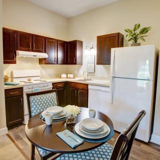 A cozy kitchen with a dining table set, featuring dark wood cabinets and modern appliances.