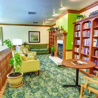 A cozy library interior with bookshelves, a fireplace, and comfortable seating.