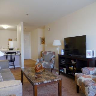 A cozy living room with a sofa, chairs, and a large television.