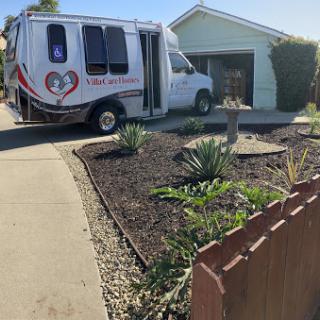 A specialized van parked in a driveway next to a well-maintained garden.