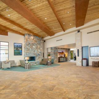 A modern and spacious lobby featuring a stone fireplace and wooden ceiling.