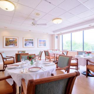 A spacious and inviting dining room with elegantly set tables and natural light streaming in from large windows.